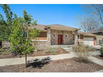 Charming single-story home with a stone facade, red front door and well-maintained landscaping at 1155 S Balsam St, Lakewood, CO 80232