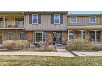 Charming townhouse featuring a brick facade, bay window, and landscaped front yard at 8862 E Amherst Dr # D, Denver, CO 80231