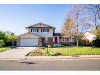 Charming two-story home featuring a well-manicured lawn and a welcoming red front door at 7328 S Kit Carson St, Centennial, CO 80122