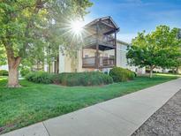 Two-story condo featuring multiple balconies, green lawn, mature trees, and sunshine at 17505 E Mansfield Ave # 1411L, Aurora, CO 80013