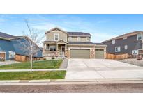 Charming two-story home with stone accents, three-car garage, manicured lawn, and inviting curb appeal at 18103 House Finch Ln, Parker, CO 80134