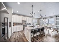 Bright kitchen with white cabinets, an island with seating, stainless steel appliances and modern pendant lighting at 18103 House Finch Ln, Parker, CO 80134