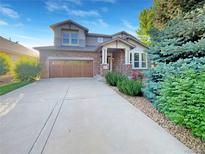 Charming two-story home featuring a stone facade, wood garage door, well maintained landscaping, and inviting entrance at 24955 E Roxbury Pl, Aurora, CO 80016