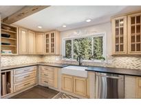 Bright kitchen with light wood cabinets, stylish backsplash, and stainless steel appliances at 34498 Forest Estates Rd, Evergreen, CO 80439