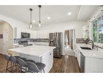 Bright kitchen features a large center island with marble countertops, stainless steel appliances, and pendant lighting at 7513 Simms Ct, Arvada, CO 80005