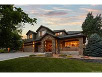 Stunning exterior elevation of stone home with a three car garage and covered front porch at sunset at 5322 Devils Head Cir, Golden, CO 80403