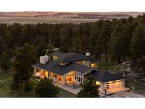 A charming home nestled among tall trees, illuminated by warm, inviting lights, with a picturesque landscape at 30886 County Road 17/21, Elizabeth, CO 80107