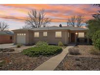 Charming brick home featuring a manicured front yard and covered entry, set against a vibrant sunset sky at 5540 E Jewell Ave, Denver, CO 80222