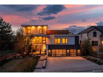 Stunning modern home featuring a sleek design, three-car garage, and beautiful landscaping against a colorful sunset backdrop at 942 S Fulton St, Denver, CO 80247