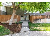 Charming townhouse featuring a brick facade, fenced-in front yard, and landscaped entrance at 8023 Wolff St # C, Westminster, CO 80031