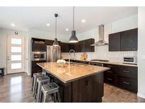 Modern kitchen featuring stainless steel appliances, dark wood cabinetry, and a large center island with seating at 9603 Dunning Cir, Highlands Ranch, CO 80126
