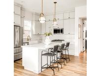 Bright kitchen features white cabinets, stainless appliances, a kitchen island with bar stool seating and modern pendant lights at 1925 W 165Th Way, Broomfield, CO 80023