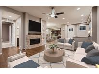 Inviting living room with a brick fireplace and modern ceiling fan, seamlessly flowing into the open kitchen at 3703 New Haven Cir, Castle Rock, CO 80109