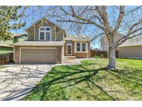 Charming two-story home boasts a well-manicured lawn, mature tree, and attached two-car garage at 5826 S Jebel Way, Centennial, CO 80015