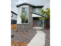 Charming two-story home with gray stone and colorful exterior featuring a red door and rock landscaping at 21011 E 63Rd Dr, Aurora, CO 80019