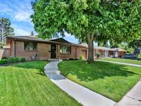 Charming single-story brick home with a well-manicured lawn and mature tree at 2046 S Quitman St, Denver, CO 80219