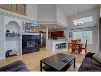 Bright open-concept living room features a fireplace, kitchen view, and dining area bathed in natural light at 19414 E Mann Creek Dr # C, Parker, CO 80134