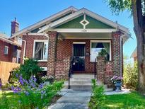 Charming brick home with a landscaped front yard featuring vibrant flowers and a welcoming entrance at 1434 Osceola St, Denver, CO 80204