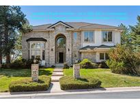 Inviting two-story brick home featuring manicured lawn and arched entry, enhancing curb appeal at 72 Falcon Hills Dr, Highlands Ranch, CO 80126