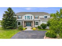 Charming two-story home showcasing a manicured lawn, brick entryway and blue double doors at 46093 Bristlecone Ct, Parker, CO 80138