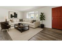 Bright living room with a cozy sectional sofa, modern artwork, and a dark wood coffee table on a light rug at 7065 Ingalls Ct, Arvada, CO 80003