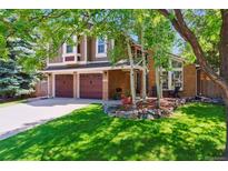 Beautiful two-story home featuring a three-car garage, brick facade, and lush green lawn at 7264 Wembley Pl, Castle Pines, CO 80108