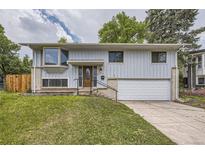 Charming home with light gray siding, brick accents, well-kept lawn, and a convenient two-car garage at 1477 S Wright St, Lakewood, CO 80228