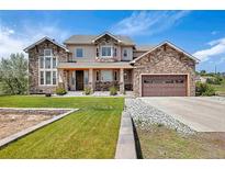 Stunning two-story home featuring a stone facade, a well-manicured lawn, and a spacious three-car garage at 7587 Wright Ct, Arvada, CO 80005