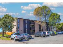 Multi-level apartment building with a parking lot and mature trees on a sunny day at 865 S Quebec St # 302A, Denver, CO 80247