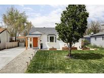 Charming home featuring a manicured lawn, vibrant orange door, and inviting curb appeal at 873 S Raritan St, Denver, CO 80223