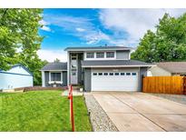 Charming two-story home with a well-manicured lawn, large driveway, and a gray and white facade at 7840 W Portland Ave, Littleton, CO 80128