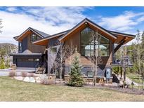 Striking mountain home with a mix of wood and dark siding and a garage beneath a gabled roofline at 2250 Highlands Dr, Breckenridge, CO 80424