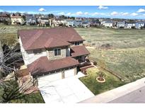 Two story home with a three car garage, brown roof, and tan and stone exterior at 10253 Fairgate Way, Highlands Ranch, CO 80126