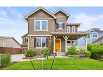 Charming two-story home with stone accents, a landscaped yard, and a welcoming front porch and yellow door at 10235 Rustic Redwood Ln, Highlands Ranch, CO 80126