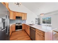 Bright kitchen boasts wood cabinets, stainless appliances, quartz counters, and eat-in dining area at 714 Sedge Way, Lafayette, CO 80026
