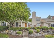 Charming home featuring stone accents, a well-manicured lawn, mature landscaping, and a welcoming front entrance at 2902 W Long Cir # B, Littleton, CO 80120