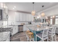 Bright kitchen features white cabinets, stainless appliances, granite counters and large island with seating at 10102 Yampa Ct, Commerce City, CO 80022