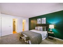 Stylish bedroom featuring green accent wall, wood headboard, bench, and cool-toned decor at 12470 E Cornell Ave # 104, Aurora, CO 80014