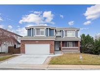 Charming two-story home featuring a brick facade, a two-car garage, and a well-manicured front lawn at 10203 Jill Ave, Highlands Ranch, CO 80130