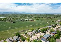 Aerial view showcasing a home nestled in a green landscape with distant mountains, lake and farms at 1264 Banner Cir, Erie, CO 80516