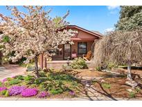 Charming brick home with a landscaped front yard featuring a flowering tree and colorful garden at 1439 S Emerson St, Denver, CO 80210