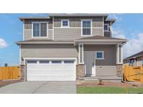 Charming two-story home boasts a white garage door, stone accents, and well-maintained landscaping at 17883 E 94Th Pl, Commerce City, CO 80022