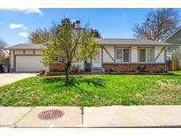 Charming single-story home featuring a well-manicured lawn, brick accents, and a quaint covered front entrance at 16650 E Nassau Dr, Aurora, CO 80013