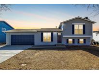 Charming bi-level home featuring a two-car garage, gray paint and blue shutters at 4752 E 108Th Pl, Thornton, CO 80233