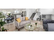 Open-concept living room with adjoining kitchen, dining area, and staircase at 4752 E 108Th Pl, Thornton, CO 80233