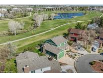 An aerial view of a two-story green home, backing up to a green area with a pond at 483 S Kingston Cir, Aurora, CO 80012
