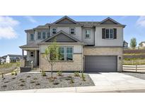 Beautiful two-story home featuring a stone facade, attached two car garage, and manicured front yard at 1694 Fox Trotter Pt, Castle Rock, CO 80104
