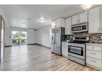 Bright kitchen with stainless appliances, white cabinets, and wood-look floors flowing into a spacious living area at 1135 S Gilbert St # 103, Castle Rock, CO 80104