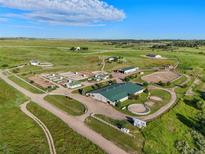 Expansive aerial view of a horse farm with paddocks, barns, outbuildings, and a well-maintained landscape at 39681 Swift Creek Cir, Elizabeth, CO 80107