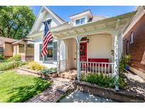 Inviting home featuring a charming front porch, red door, and beautiful landscaping at 3145 W 23Rd Ave, Denver, CO 80211